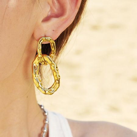 Stainless Steel Chunky Gold Elliptical Interlock Charm Drop Earrings (5 Pairs) - Close-up of a chunky gold elliptical interlock charm drop earring made from stainless steel, showcasing its textured finish.