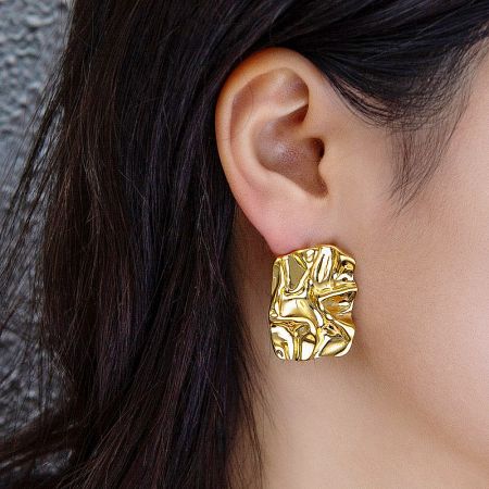 A model wearing the gold textured chunky stud earring, highlighting its bold look.