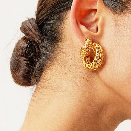 Another angle of the C-shaped gold earring being worn, highlighting its lustrous finish.