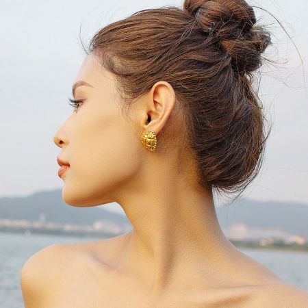 Model wearing the gold metallic plaid love heart stud earring to showcase its size and style.