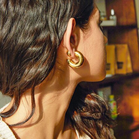 Detailed product shot of the gold chunky ball stud and crescent hoop earring set.