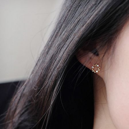 Side view of a gold wreath stud earring showcasing a clear gemstone.