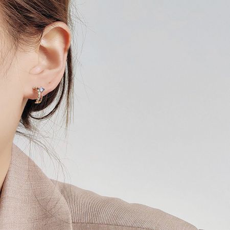 Close-up of a single gold stud earring showcasing a brilliant clear gemstone.