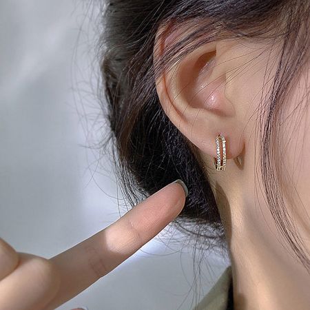 A model wearing the gold double row rhinestone hoop earring to showcase its size and fit.