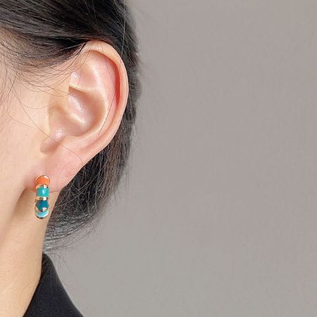 Close-up of a woman wearing a colorful enamel bamboo hoop earring, highlighting its fit and style.