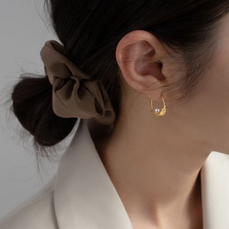 Side view of the gold pearl feather C-hoop earring showcasing its elegant curve.