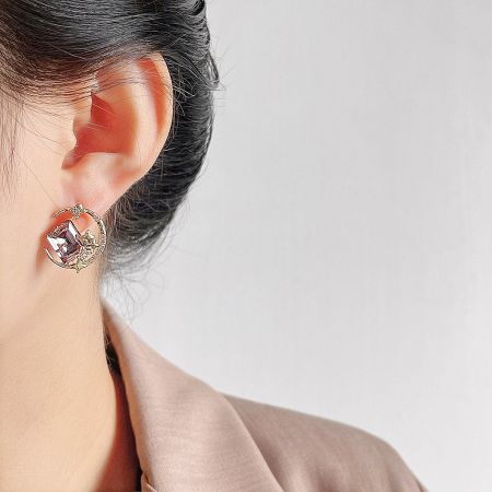 Another perspective of a single gold-plated stud earring with a vibrant pink crystal.