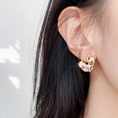 Model wearing the gold earring with pink gemstones to show scale and style.