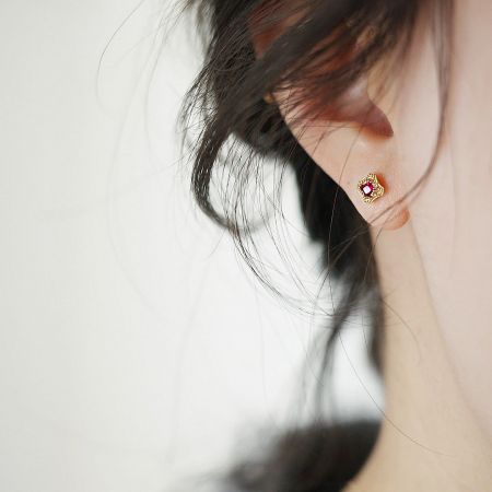 Side profile of a single mini gold stud earring with a vibrant ruby red stone.