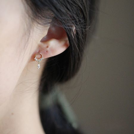 Close-up of the gold zircon teardrop hoop earring being worn to showcase its elegant drop and sparkle.