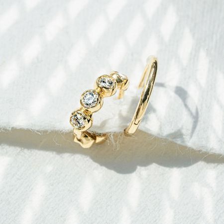 Detailed view of a single bezel-set CZ hoop earring highlighting the craftsmanship.