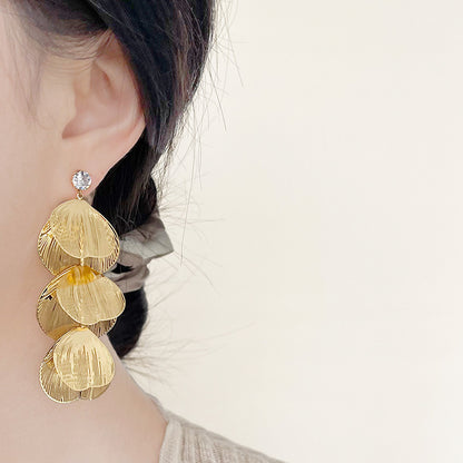 A single gold drop earring featuring three stacked, textured discs.