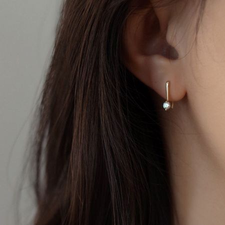 Close-up of a woman wearing a 14K gold plated sterling silver hook earring, highlighting its sparkle.
