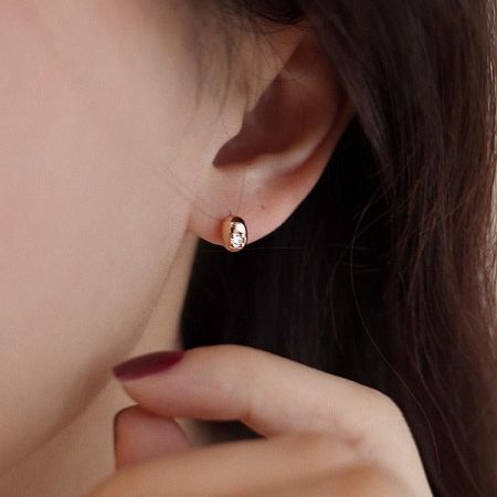 Close-up of the gold bean-shaped stud earring worn to showcase its sophisticated look.
