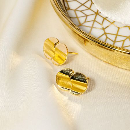 Lifestyle product shot of the gold double disc earrings placed next to a decorative dish, highlighting their aesthetic appeal.