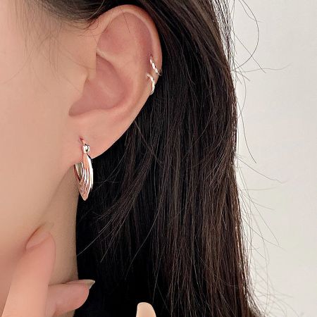 A model wearing the geometric hoop earrings, highlighting their scale and style.