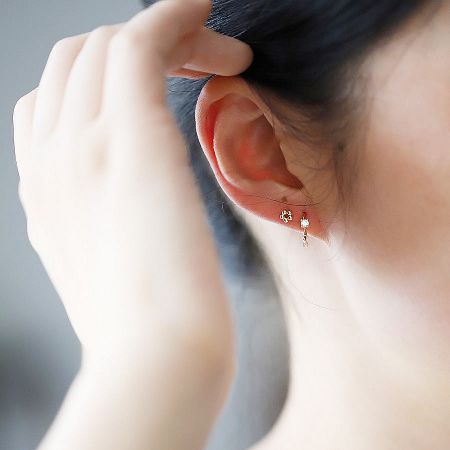 Detailed view of a gold flower stud earring and a dangling gemstone earring from the 5-piece set.