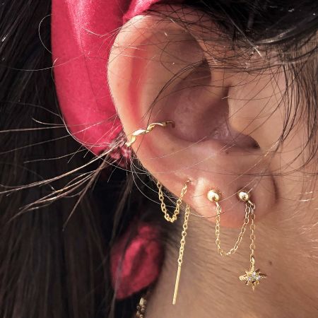 The gold star pendant earrings styled on a model's ear, demonstrating their elegant drop.