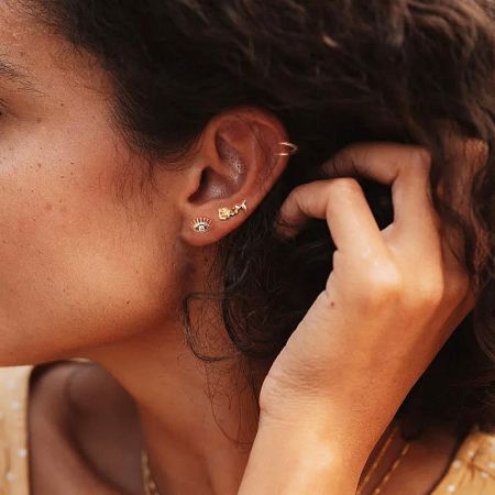 A model showcasing a stylish ear stack with gold-plated sterling silver earrings, highlighting the small eye zircon stud.