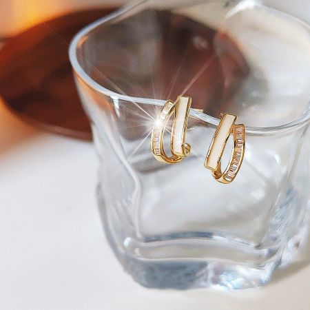 Lifestyle photo of the white enamel gold cross earrings elegantly displayed.