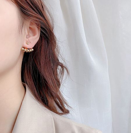 A model wearing the gold ball ear jacket earrings to showcase their style and fit.
