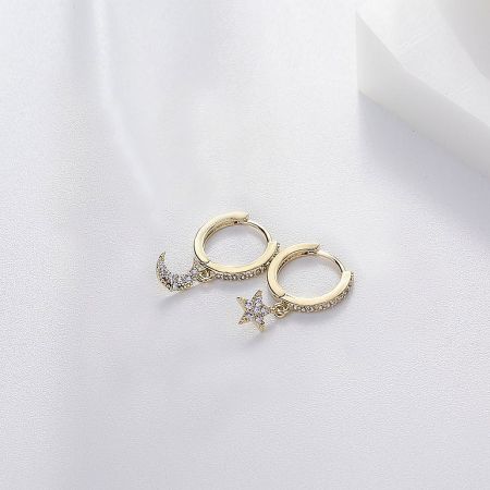 A stylish display of the gold Moon and Star Huggie Earrings against a neutral background.