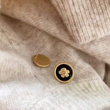 Wholesale 14k Gold Matte Black Enamel Flower Stud and Clip Earrings (5 Pairs) - A pair of 14k gold plated flower earrings with matte black enamel, displayed on a textured beige fabric, showcasing both stud and clip-on variants.