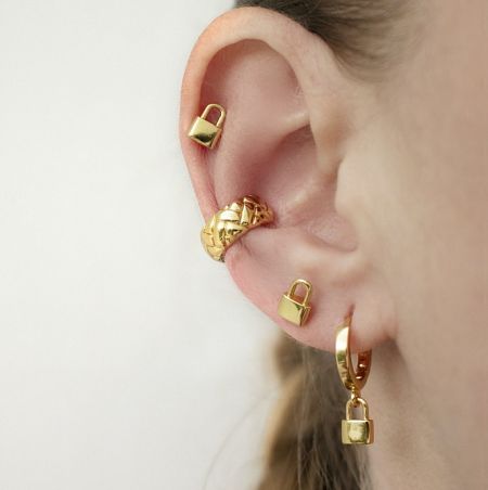 Close-up view of the gold padlock and hoop earrings on an ear.
