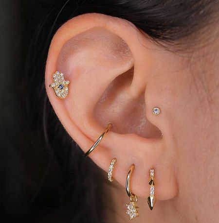 Close-up view of the gold-plated huggie earrings with cubic zirconia, demonstrating their detailed craftsmanship on an ear.