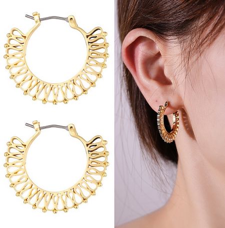 Close-up of a model wearing an elegant, round 18K gold-plated earring with an engraved design.