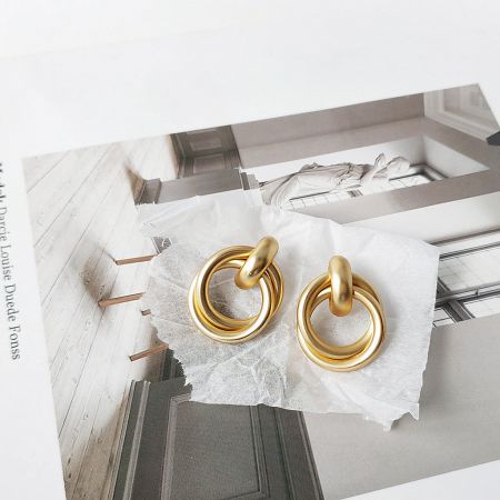 Studio product shot of the matte gold-plated geometric knot earrings against a white background.