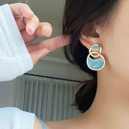 Close-up view of the blue enamel interlocking circle stud earrings.