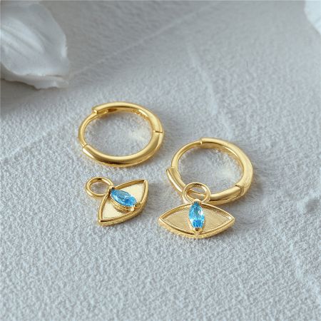Another style of gold huggie earrings featuring dangling blue gemstone charms.