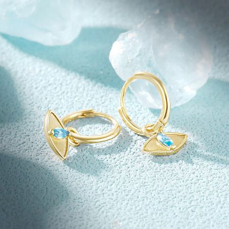 Product shot of the gold evil eye huggie earrings against a plain background.