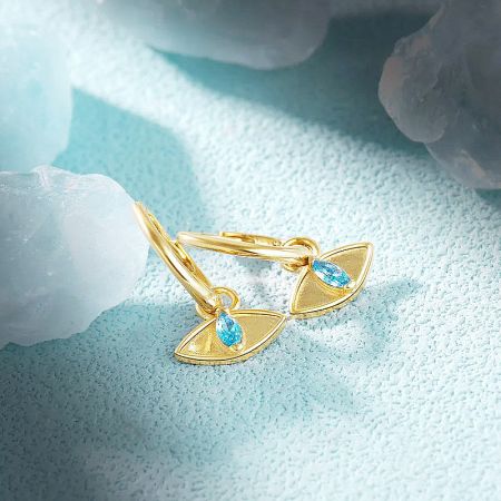 Front view of the gold huggie earrings with vibrant blue gemstones.