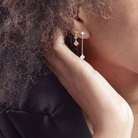 Model showcasing a pair of gold earrings with multiple charms, demonstrating how they look when worn.