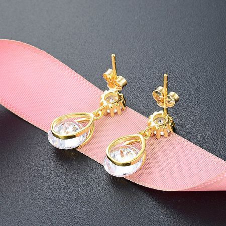 A pair of gold-plated teardrop earrings with white zirconia, shown from a different angle.