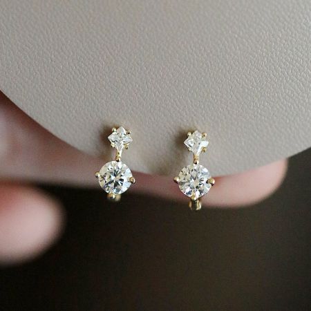 Detailed shot of the 925 sterling silver huggies with square and round clear gemstones.