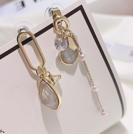A detailed close-up of the Dainty Geometric Resin Earrings, highlighting the clear teardrop stones and intricate gold detailing.