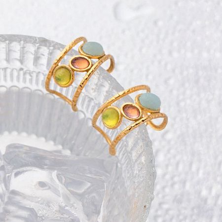 Detailed shot of the three-color opal stone earrings displayed on a clear ridged glass dish.