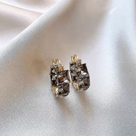 A pair of gold earrings with large, rectangular dark gemstones.