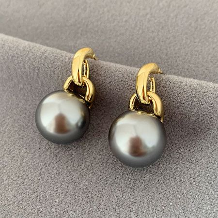 Elegant gold earrings paired with sophisticated dark gray pearls.