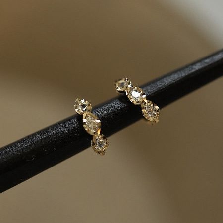 A pair of the triple teardrop CZ huggie earrings displayed, showcasing their brilliant shine.
