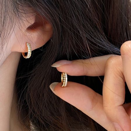 Model showcasing the 18k gold plated CZ huggie hoop earrings for a stylish look.