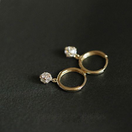 A pair of circular gold hoop earrings with clear gemstones from the collection.