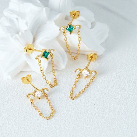 Elegant gold earrings with dangling chains, available with green and clear sparkling gemstones.