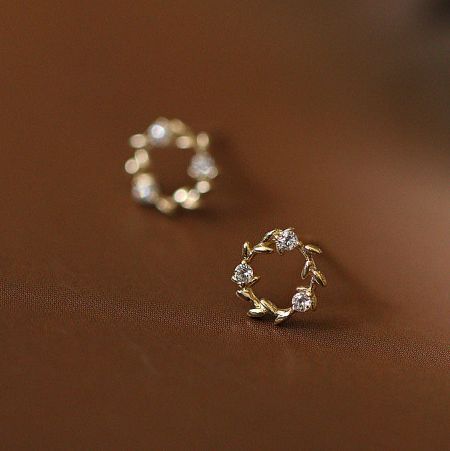 A pair of gold wreath earrings with clear gemstones and detailed leaf accents.