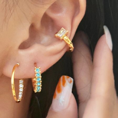 A model's ear adorned with multiple earrings, including the featured C-shape hoops, for a layered look.