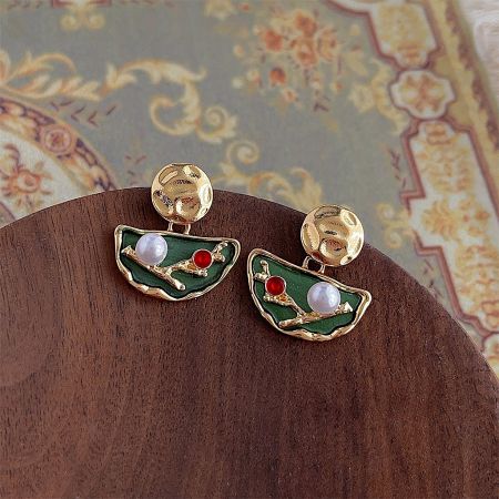 Angled shot of the enamel and pearl drop earrings, highlighting the branch-like gold structure.