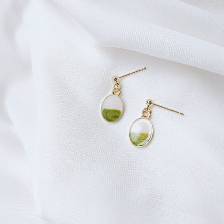 A pair of gold earrings featuring a unique design with green pendants, highlighting their earthy and natural aesthetic.